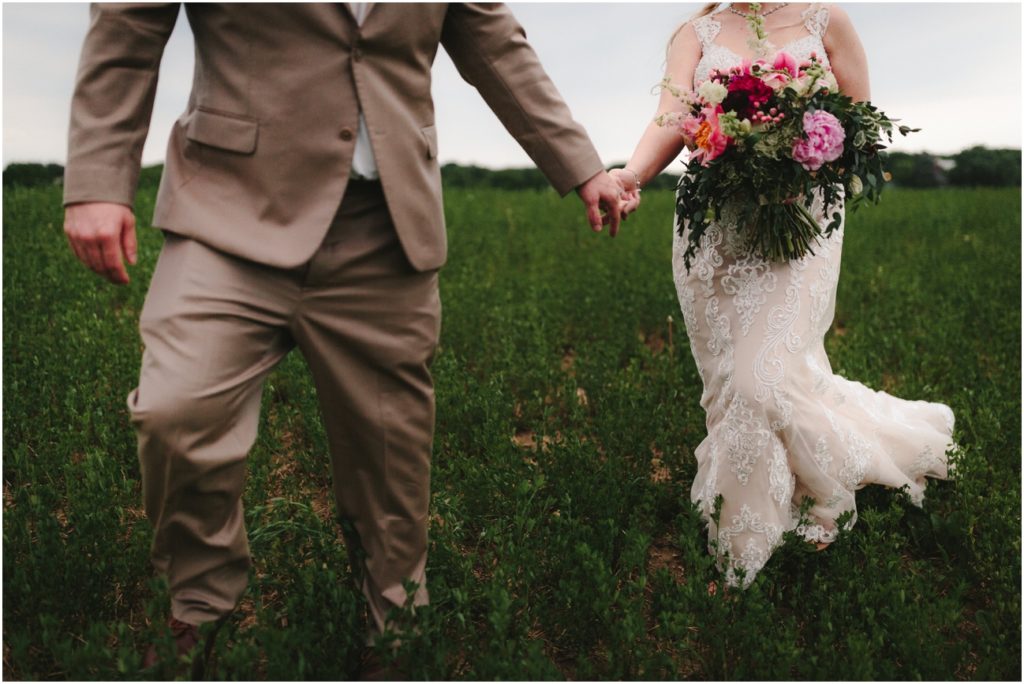 Groom leading his bride through a field.