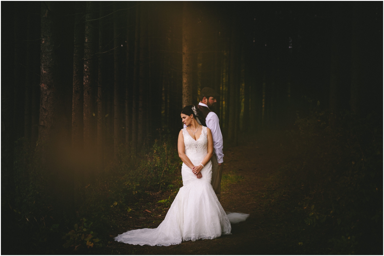 Wedding couple posed together in the woods for a stylized portrait